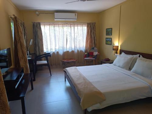 a hotel room with a bed and a desk and a window at Chai Seeds Resort in Mākum