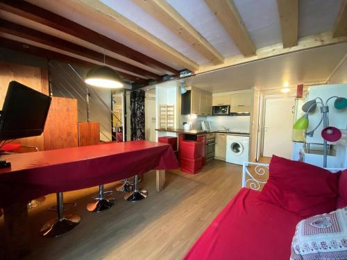 a living room with a red table and a bed at Résidence Altineige - 3 Pièces pour 6 Personnes 31 in Val Thorens