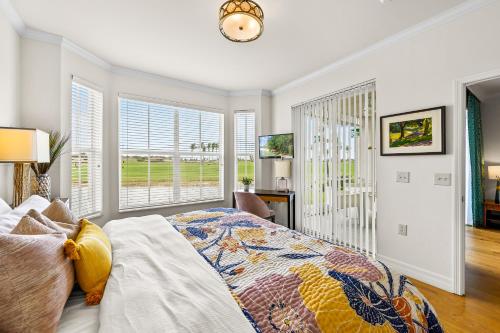 a bedroom with a bed and a desk and windows at Catina Golf Condo at the Lely Resort in Naples