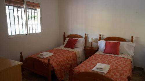two twin beds in a room with a window at El Higuerón (Serranía de Ronda) in Jimera de Líbar