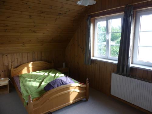 - une chambre avec un lit dans une pièce en bois dotée de 2 fenêtres dans l'établissement Warthe - Mitten in der Natur, à Warthe