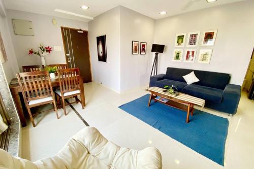 a living room with a blue couch and a table at Westside 2 BHK Condo with Balcony at Chaple Road Bandra West by Connekt Homes in Mumbai