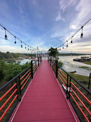 a red bridge with lights over a river at ปลายเขื่อนแคมป์ปิ้ง บ้านเรือไทย in Sirindhorn