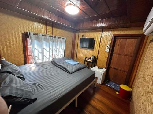 Sirindhornにあるปลายเขื่อนแคมป์ปิ้ง บ้านเรือไทยの小さなベッドルーム(ベッド1台、テレビ付)