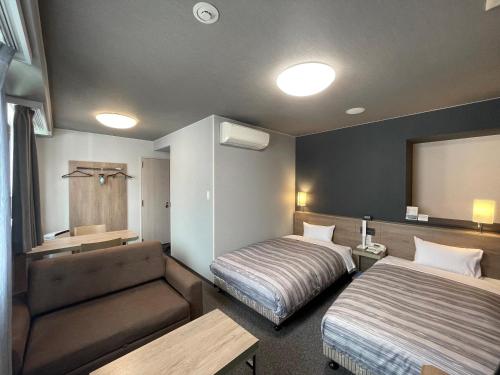 Habitación de hotel con 2 camas y sofá en Route Inn Grantia Naha, en Naha