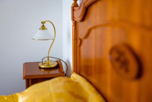 a lamp on a night stand next to a bed at Complex Vața Băi in Vaţa de Jos