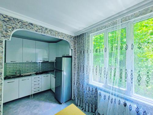 a kitchen with a refrigerator and a large window at Family hotel mountain panorama in Borjomi