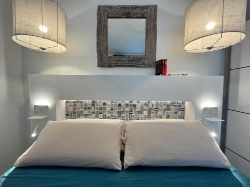 a bedroom with a white bed with a mirror and lights at Barbican in Playa Honda