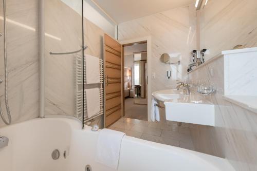 a bathroom with a tub and a sink and a shower at Hotel Olympia in Obergurgl