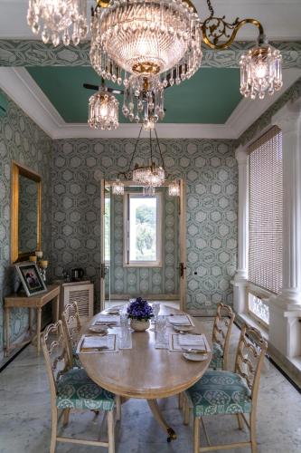 a dining room with a table and chairs and a chandelier at Rajmahal Palace RAAS in Jaipur
