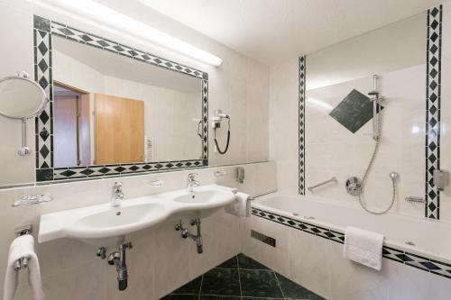 a bathroom with two sinks and a tub and a mirror at Hotel Olympia in Obergurgl