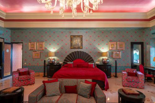 a bedroom with a red bed and a couch at Rajmahal Palace RAAS in Jaipur
