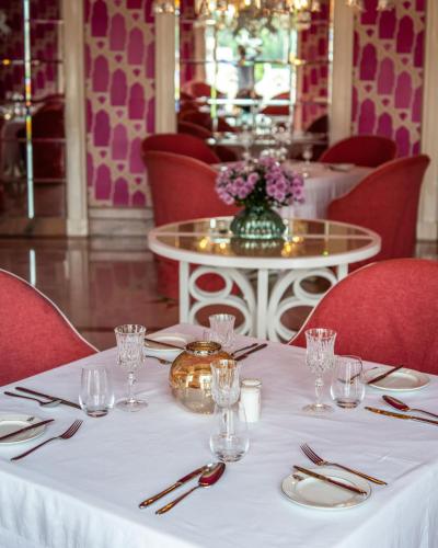 a table in a restaurant with a white tablecloth and red chairs at Rajmahal Palace RAAS in Jaipur