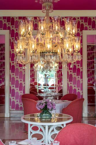 a pink dining room with a table and chandelier at Rajmahal Palace RAAS in Jaipur