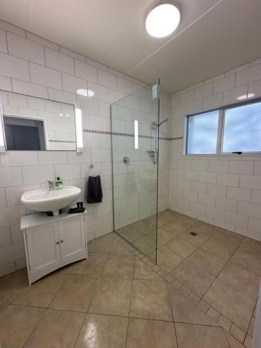uma casa de banho com um lavatório e uma cabina de duche em vidro. em Foreshore Mukies 2,0 em Ahipara