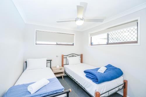 two beds in a room with white walls and a window at 3BR Family Oasis: Pool, BBQ, Central Gold Coast Fun! in Gold Coast
