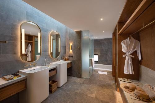 a bathroom with two sinks and two mirrors at Sumitra Luxury Villas & Resort by Pramana in Sanur