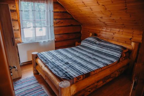a bed in a log cabin with a window at Cabana La Matei in Suceava