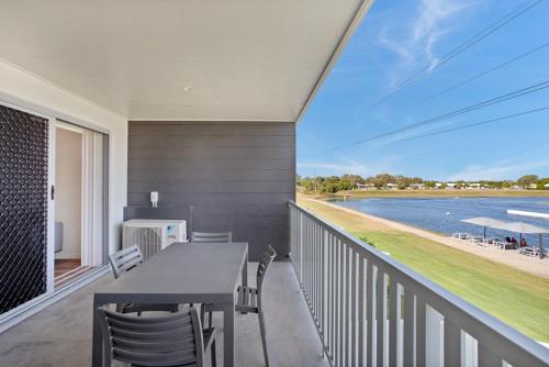 balcón con mesa, sillas y vistas al agua en Lake Poco Apartments, en Mackay