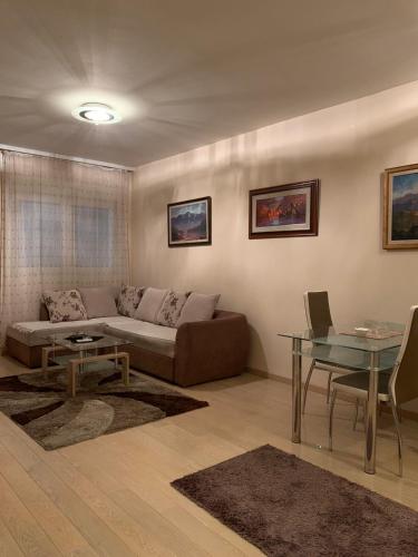 uma sala de estar com um sofá e uma mesa de vidro em Beko City em Podgorica