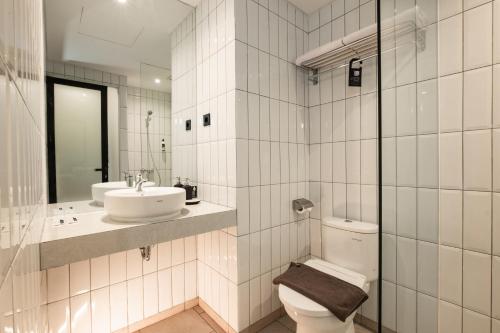 a white bathroom with a toilet and a sink at Assa Hotel in Semarang