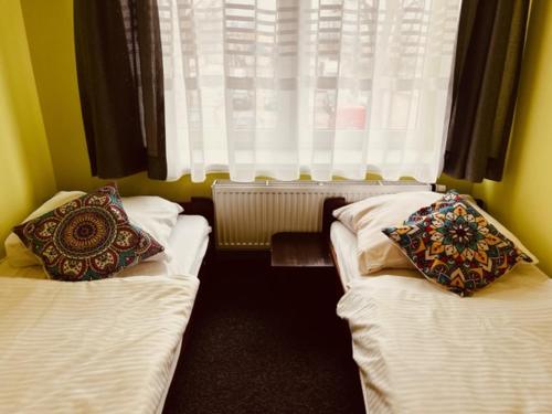 a room with two beds with pillows and a window at Royal House in Białogard