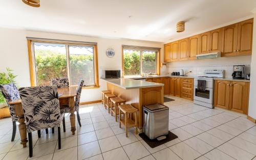 a kitchen with wooden cabinets and a table and chairs at Kiama Cottage beside the Bay in St Helens