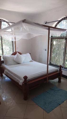 uma cama de dossel num quarto com janelas em BBQ Lounge em Dar es Salaam