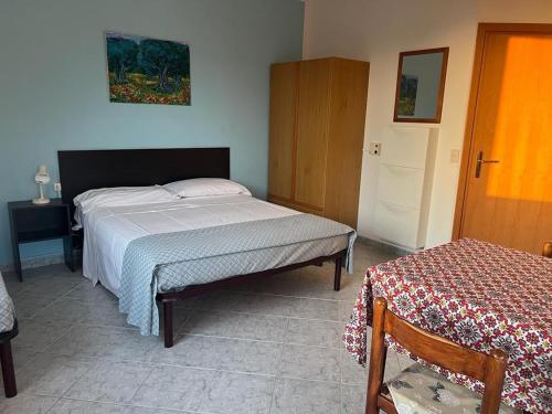 a bedroom with a bed and a table and a door at Villetta Fichera Monolocale in Gioiosa Marea