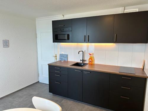 a kitchen with black cabinets and a sink at Lakeside Apartments Rorschach - easy self check-in in Rorschach