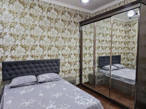 1 dormitorio con cama y espejo en Новая 3-х комнатная квартира Мечта, en Bukhara