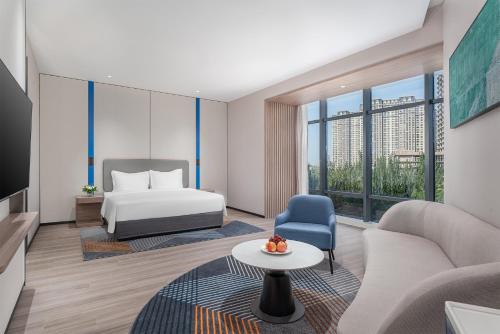 銀川市にあるHoliday Inn Express Yinchuan Yuehaiのベッド、ソファ、テーブルが備わるホテルルームです。