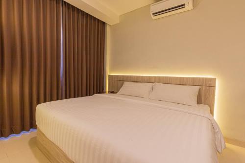 a bedroom with a large white bed and a window at The Baliem Hotel in Jimbaran