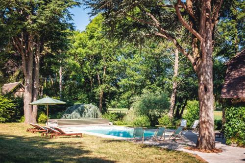 - une piscine dans une cour avec des chaises et un parasol dans l'établissement VILLA ROMAN, à Authenay