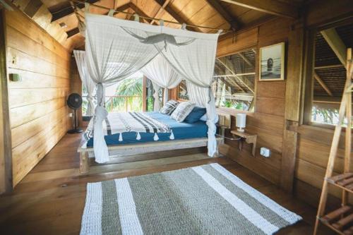 a bedroom with a bed with a canopy at Favela Mentawai in Tua Pejat