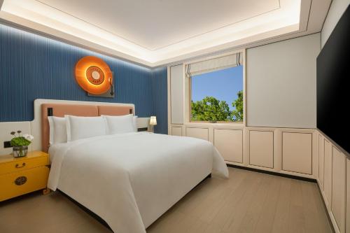 a bedroom with a large white bed and a window at Hotel Indigo Guangzhou Haixinsha by IHG - Free Shuttle Bus to Canton Fair Complex during Canton Fair period in Guangzhou