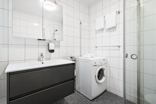 a white bathroom with a washing machine and a sink at Enter Amalie Apartment Hotel in Tromsø