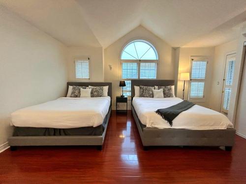 two beds in a room with two windows at Spacious Detached House in Mississauga in Mississauga