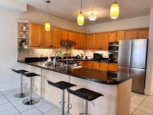 a kitchen with a stainless steel refrigerator and bar with stools at Spacious Detached House in Mississauga in Mississauga