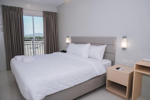 een slaapkamer met een groot wit bed en een balkon bij Ma. Awani Hotel & Suites 