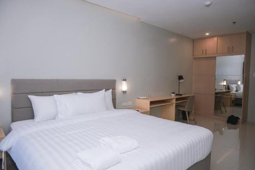 にあるMa. Awani Hotel & Suitesのベッドルーム(白い大型ベッド1台、デスク付)