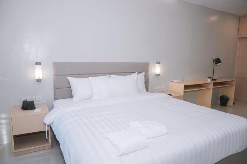 een groot wit bed met twee witte handdoeken erop bij Ma. Awani Hotel & Suites 
