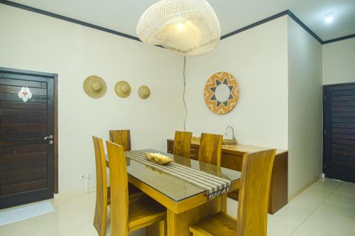 a dining room with a wooden table and chairs at GILI VIEW By Kalma in Teluknarat
