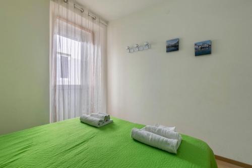 a bedroom with a green bed with two towels on it at Appartamento Al porticciolo in Grado