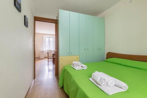 a bedroom with a green bed with towels on it at Appartamento Al porticciolo in Grado