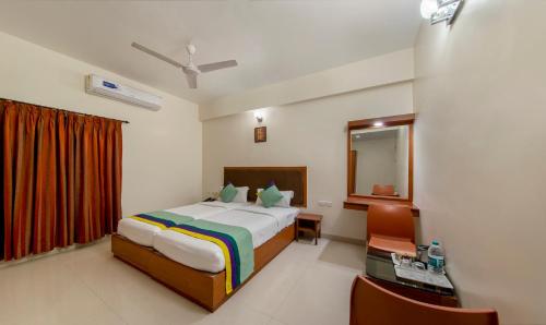a hotel room with a bed and a mirror at Treebo Sam Residency in Coimbatore