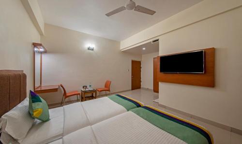 a hotel room with a bed and a flat screen tv at Treebo Sam Residency in Coimbatore