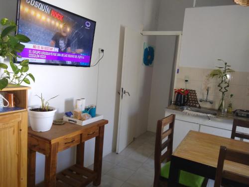 a kitchen with a table and a tv on the wall at Casa familiar cerca de las termas in Dolores