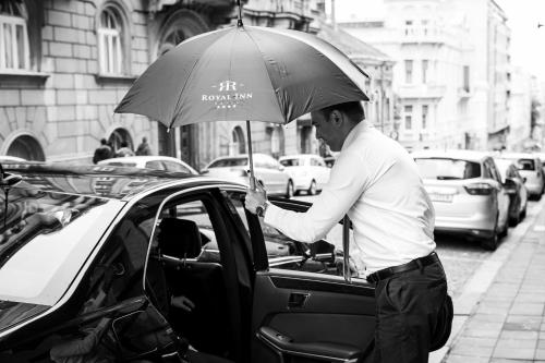 a man is getting into a car with an umbrella at Hotel Royal Inn in Belgrade