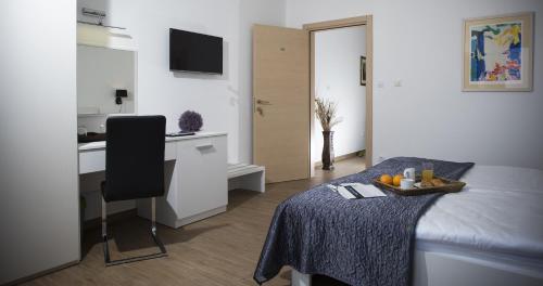a bedroom with a bed and a desk and a kitchen at Comfort Zovko in Mlini